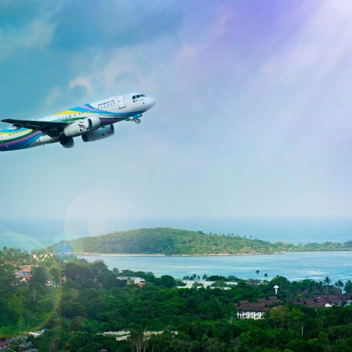 Airplane soaring over Koh Samui island, Thailand, showcasing a vibrant tropical landscape in daylight.
